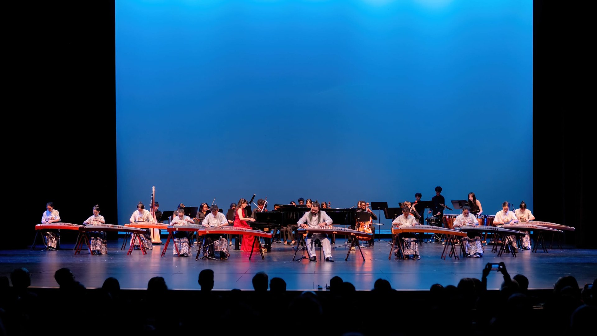 Guzheng ensemble performing under blue stage lights at Music of Love 2026